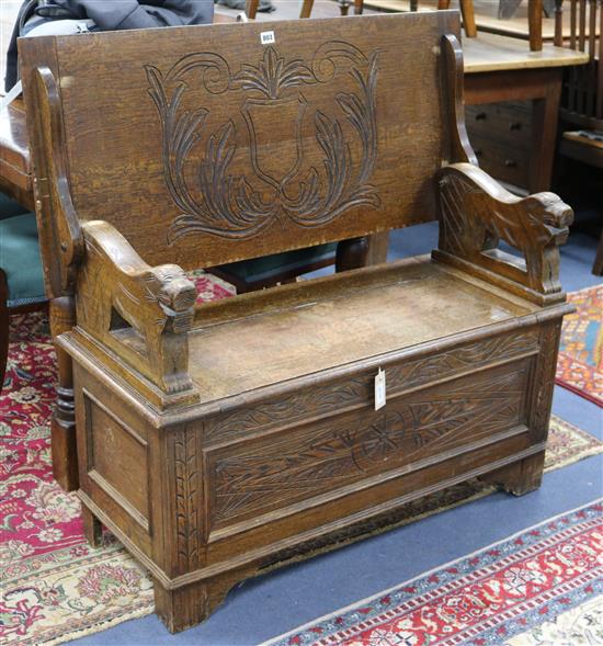 A carved oak monks bench W.105cm.